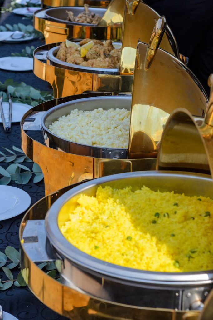 pexels photo 12253094 12253094 A vibrant buffet spread featuring yellow rice and various options in elegant chafing dishes.